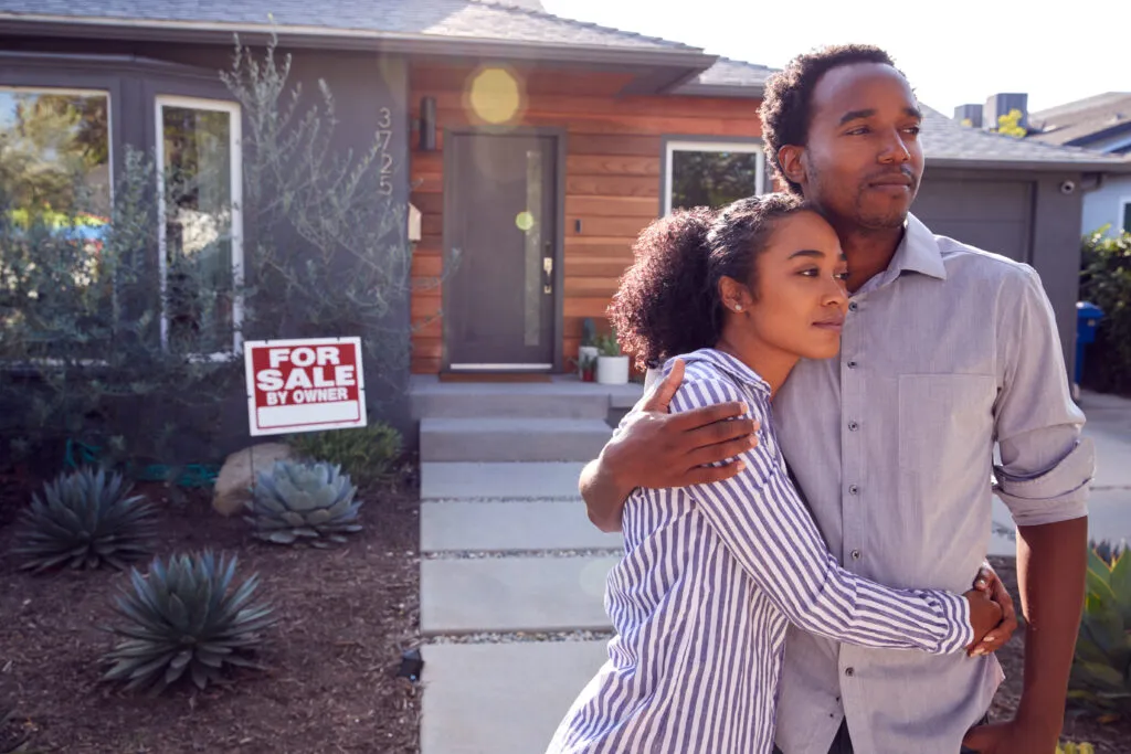 Two people in front of a house for sale